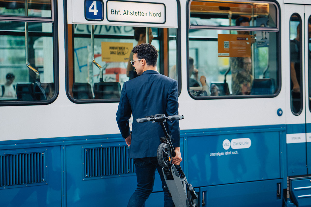 image d'un individu s'apprêtant à entrer dans un bus avec sa trottinette électrique