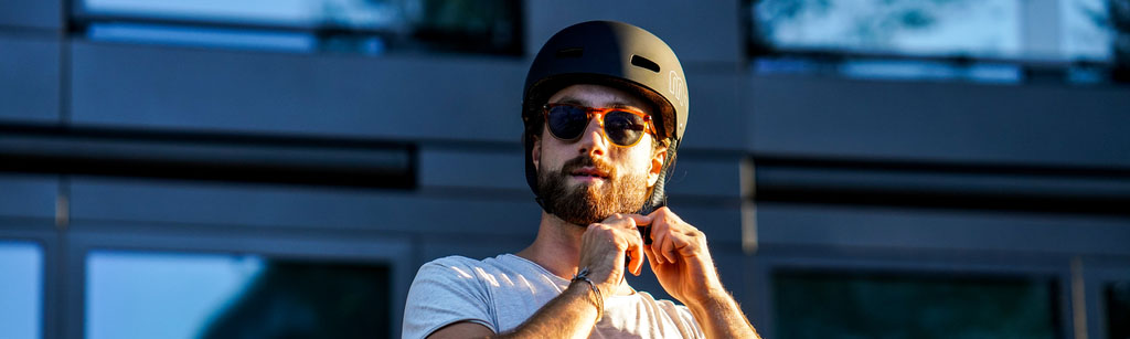 photo d'un adulte qui enfile un casque de trottinette micro