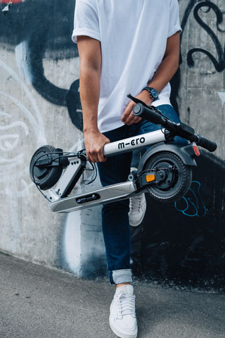 image d'un homme qui tient une trottinette électrique pliée