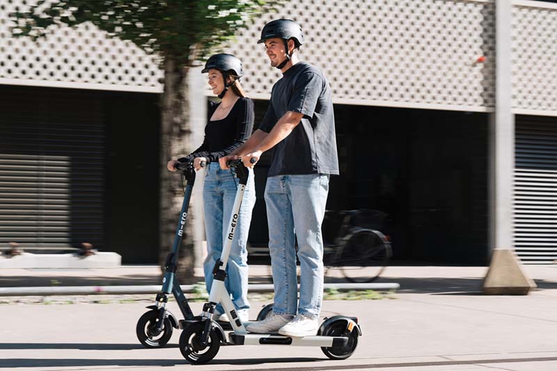 deux individus qui font de la trottinette électrique